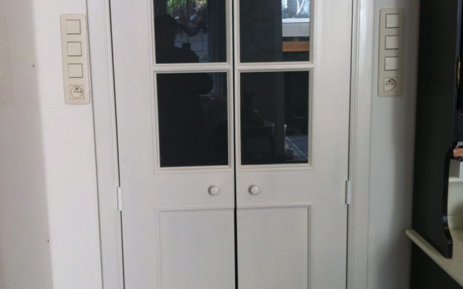 Transformation d'une porte tubulaire en doubles portes battantes avec vitrages et panneaux. Peinture réalisée en atelier.
